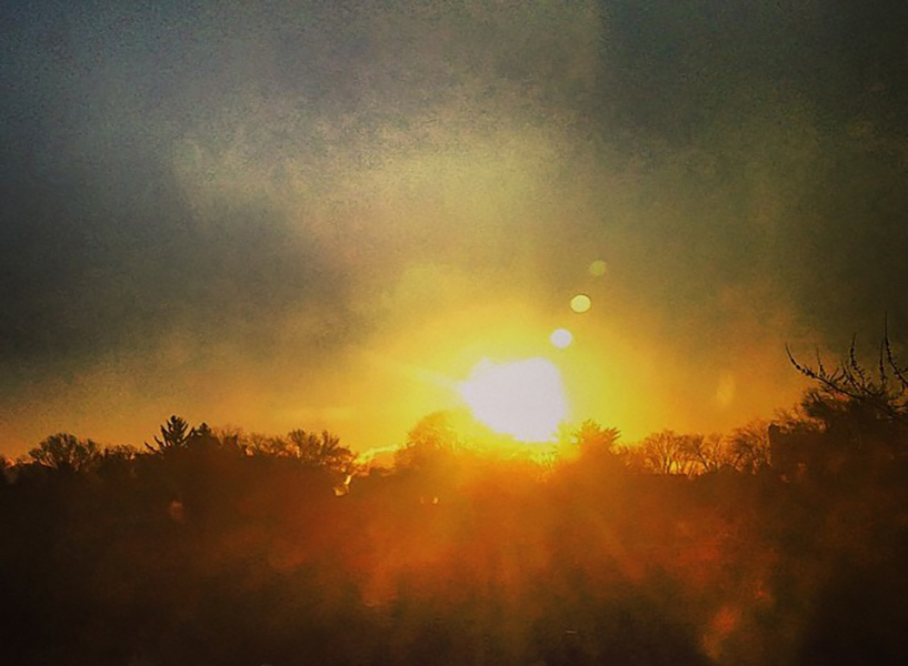 photo of a sunrise over a distant treeline